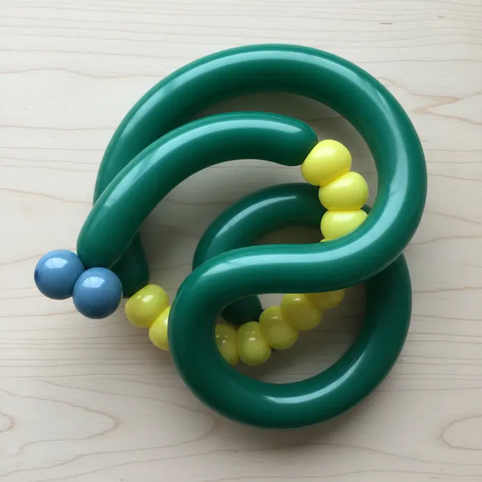 A long green balloon animal shaped like a snake, coiled on a flat surface.